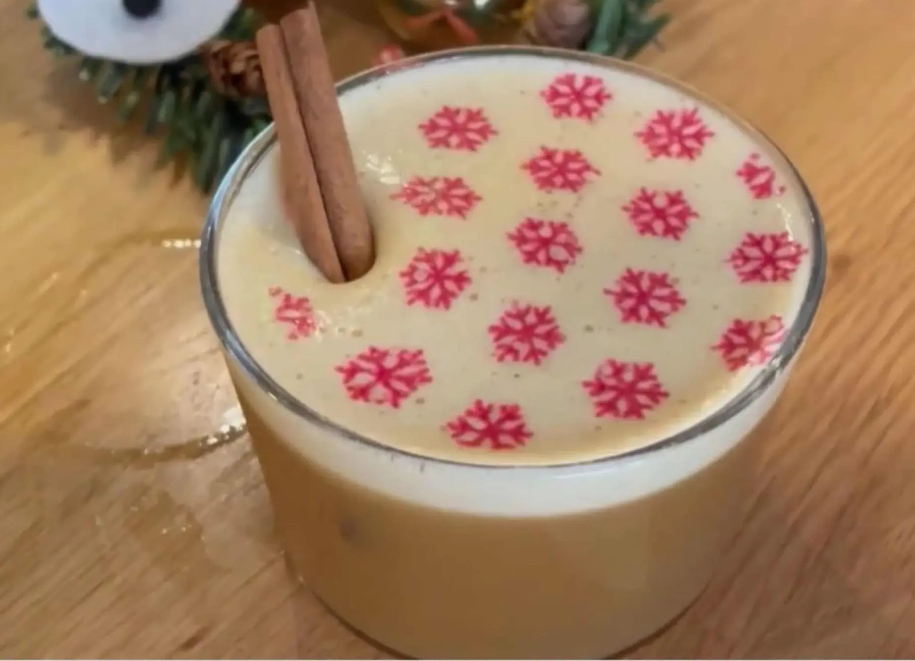 Foam-topped winter drink with snowflake print and cinnamon stick