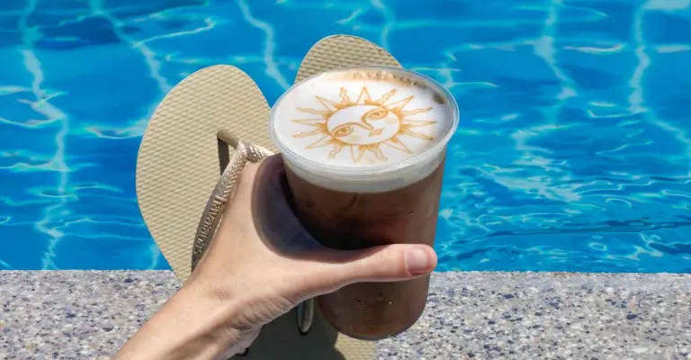 Cold Foam-Topped Cold Brew with a Ripples Print. The drink and flip-flops are held near a pool